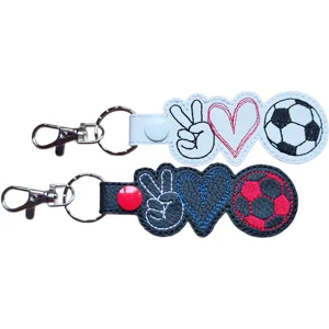 Two Football Peace Love faux leather keyrings in black and white, featuring embroidered peace sign, heart and football designs.