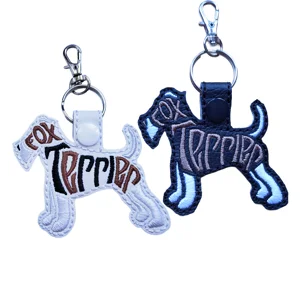 Fox Terrier word art keyrings shown in white and black faux leather with embroidered details and sturdy metal clasps.