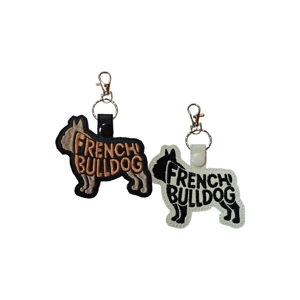 French Bulldog keyring made from embroidered faux leather, showing a stitched word-art silhouette that reads “French Bulldog,” displayed in black and white colour options with metal clasp and keyring.