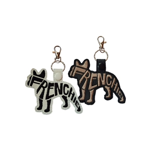 Frenchie keyrings in black and white faux leather, featuring embroidered word-art silhouettes with metal clasps and keyrings, shown side by side.