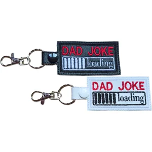 Two Dad Joke Loading keyrings shown in black and white faux leather with embroidered loading bar designs and metal lobster clasps.