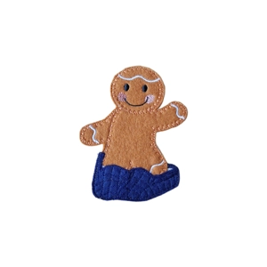 A felt Gingerbread Child Wearing Dad’s Slippers Character, featuring a smiling gingerbread with rosy cheeks, white icing details, and oversized blue quilted slippers. The handcrafted decoration is made from soft brown felt with delicate embroidered stitching.
