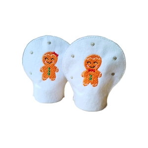 Pair of embroidered Gingerbread Christmas Tealight Covers made from white felt, featuring a smiling gingerbread boy with a red bowtie and a gingerbread girl with a red bow, surrounded by small silver stars.
