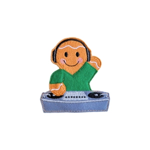 A handmade felt gingerbread character dressed as a DJ, wearing headphones and a green top, standing behind grey turntable decks with embroidered details.