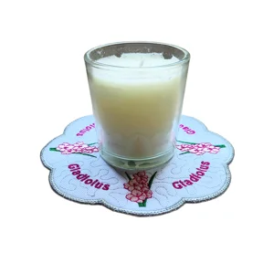 Embroidered gladiolus candle mat with scalloped grey edge, pink flower detail, personalised Gladiolus text and a glass candle displayed in the centre.