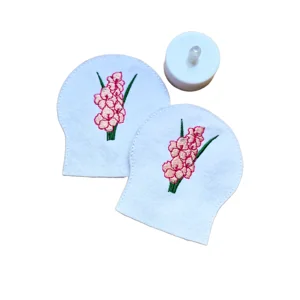Pair of white felt Gladiolus tealight covers shown with a standard LED tealight, featuring pink embroidered flowers and green leaves.