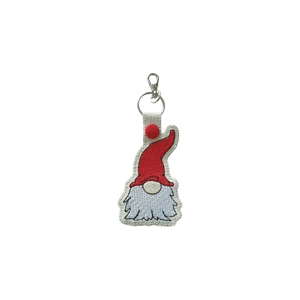 White faux leather keyring shaped like a gnome with a tall red hat, fluffy embroidered white beard, and beige nose, finished with a red snap and silver keyring clasp.