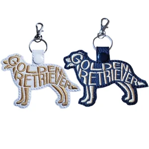 Golden Retriever word art keyrings shown in white and black faux leather with embroidered details and sturdy metal clasps.