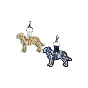 Golden Retriever embroidered faux leather keyrings in white and black, featuring stitched word-art dog silhouettes with metal clasps and keyrings, shown side by side.