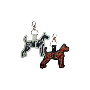 Two embroidered Great Dane silhouette keyrings, one white and one black, with the words ‘Great Dane’ stitched into the design and finished with a metal clasp.
