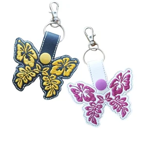 Black and white Hibiscus Flower Butterfly keyrings with floral embroidery, faux leather straps, snap button details and metal lobster clasps.