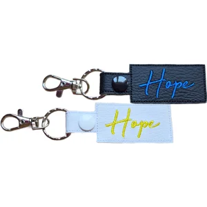 Black and white faux leather Hope positive word keyrings with embroidered text and metal clip attachments.