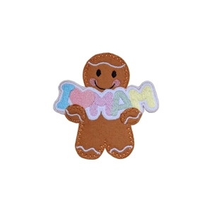 A felt gingerbread character holding an embroidered ‘I ♥ MAM’ banner, with stitched icing details, a smiling face, and rosy cheeks.