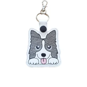 Kawaii border collie dog keyring made from white faux leather with black embroidered markings, bright eyes, pink tongue, keyring and lobster clasp.