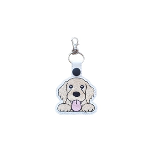 Embroidered keyring featuring a cute kawaii-style Golden Retriever with floppy ears and a tongue-out smile, attached to a white faux leather strap with a metal clasp.