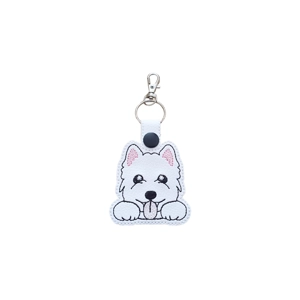 A faux leather keyring featuring a kawaii-style West Highland Terrier (Westie) pup with stitched details, including shiny black eyes, fluffy white fur, pink inner ears, small paws, and a tiny tongue sticking out. The keyring has a white snap tab, metal keyring, and a small lobster clasp at the top.