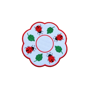 Embroidered ladybird decorative table mat with red ladybirds and green leaves on a stippled fabric background, scalloped red border.