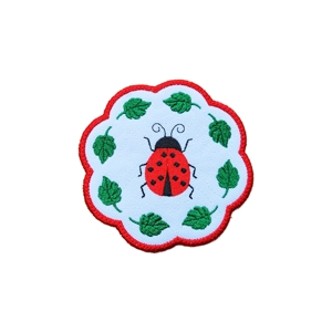 Ladybird Leaf Coaster Mat with a scalloped edge, featuring one large embroidered red ladybird in the centre surrounded by green leaves on white fabric.