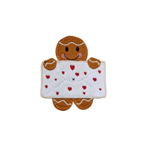 Love Letter Gingerbread Character – a handmade felt gingerbread figure holding a white felt envelope decorated with small embroidered red hearts. The gingerbread has stitched icing-style details, pink cheeks, and a smiling expression.