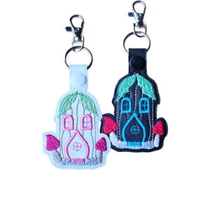 White and black faux leather fairy house keyrings with colourful embroidered door, window, roof and toadstool details.