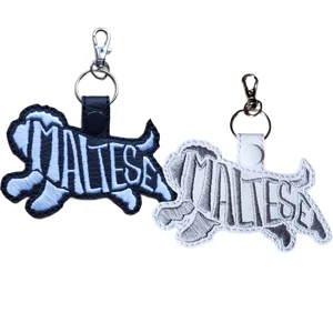 Two Maltese word art dog keyrings in black and white faux leather, with embroidered breed designs and metal clasp fittings.