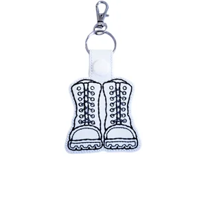White military combat boots keyring with black embroidered detail, white popper fastening and silver metal keyring clasp.