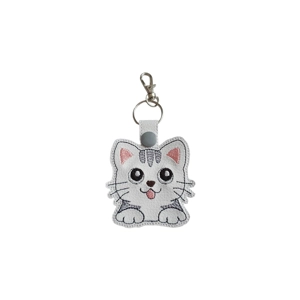 A kawaii-style cat keyring made from white faux leather, featuring a cute cat face with large black eyes, a small pink tongue, whiskers, and darker grey stitched markings on the head and body. The cat has pink inner ears, stitched paws at the bottom, and is finished with a metal keyring and lobster clasp.
