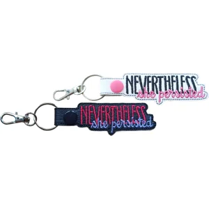 Black and white Nevertheless She Persisted keyrings with embroidered quote lettering, colourful thread options, popper fastenings and silver metal clasps.