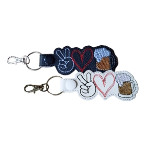 Two faux leather keyrings with a peace sign, a heart, and a frothy beer mug. One keyring has a black base with white, red, brown, and grey stitching, the other has a white base with black, red, brown, and grey stitching. Both have metal key rings and lobster clasps.