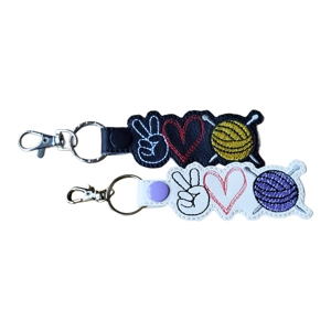 Two faux leather Peace Love Knitting keyrings featuring a peace sign hand, stitched heart and ball of yarn motif with knitting needles, finished with embroidered details and a metal ring and lobster clasp.