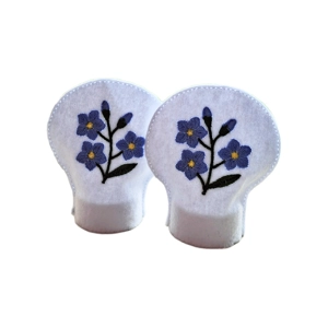 Two white felt LED tealight covers embroidered with delicate blue forget me not flowers, shown side by side.