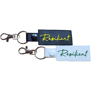 Black and white faux leather Resilient positive reminder keyrings with embroidered lettering, metal clasps and matching popper fastenings.