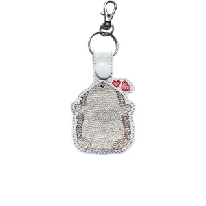 Embroidered faux leather hedgehog keyring with red heart details, attached to a metal clasp and ring.