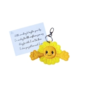 A smiling sunflower pocket hug keyring made from yellow felt with open arms, attached to a silver keyring clip, shown alongside a printed keepsake card with a comforting message.