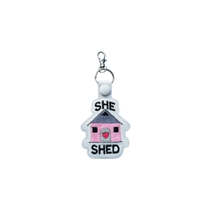 Embroidered she shed keyring with a small shed motif and text, made from faux leather and attached to a metal keyring clasp.