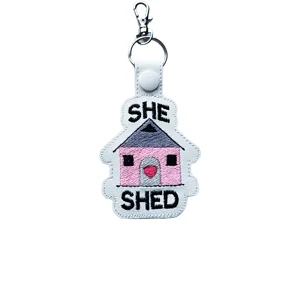 She Shed keyring made from faux leather, with an embroidered pink shed design, black text and sturdy metal keyring and lobster clasp.