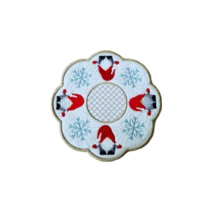 Embroidered circular candle table mat featuring four festive gnomes in red hats surrounded by blue snowflakes and a gold-edged scalloped border, with an intricate stippled pattern in the centre.