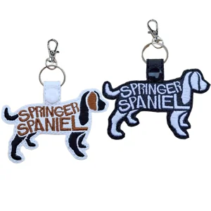 Springer Spaniel word art keyrings shown in white and black faux leather, with embroidered dog-shaped designs and silver keyring clasps.