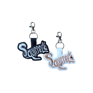 Two squirrel word art keyrings, one in black and one in white, with the word “Squirrel” stitched to form the shape of a squirrel, each finished with a metal clasp and keyring.