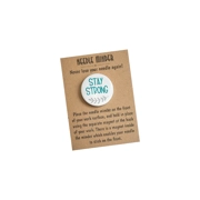A round 38 mm needle minder with the words “Stay Strong”, finished with a small grey leaf motif, presented on a kraft backing card.