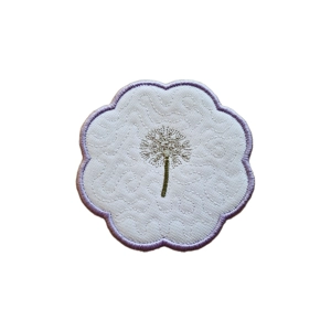 A round candle coaster with a softly scalloped edge, made from white fabric with a subtle stitched texture. At the centre is a delicately embroidered dandelion seed head with a fine green stem, surrounded by a pale lavender stitched border.