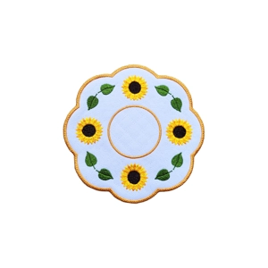 Round embroidered sunflower decorative table mat with scalloped edges, yellow border, and green leaves on a white background.