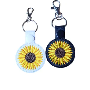 Black and white sunflower keyrings made from faux leather, with embroidered yellow sunflower designs and metal keyring hardware.