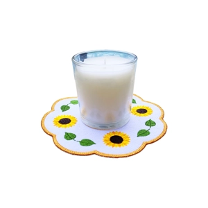 A round embroidered candle mat featuring bright yellow sunflowers and green leaves arranged around the edge, shown with a glass candle placed at the centre.