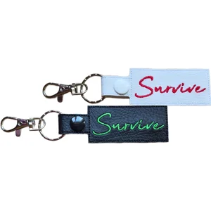 Black and white faux leather Survive positive reminder keyrings with embroidered lettering, metal clasps and matching popper fastenings.