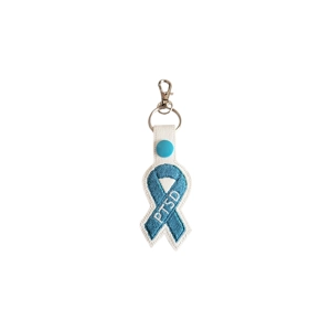 Teal PTSD awareness ribbon keyring with the letters “PTSD” embroidered on the ribbon, made in teal stitching on a light faux leather backing, finished with a metal keyring and clasp.