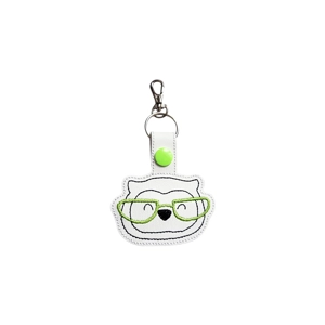 An embroidered owl keyring with a smiling owl face wearing green glasses, made from white faux leather and shown on a plain white background.