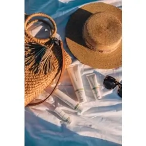 Rodan and Fields Soothe Calming Gel Cleanser product line on the beach with a purse and hat next to the products