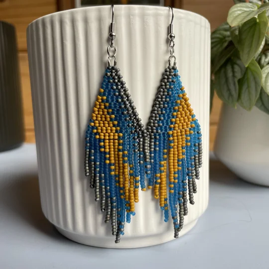 A pair of handmade beaded fringe earrings. Colors in a gradient Grey, Frosted Blue, and Mustard