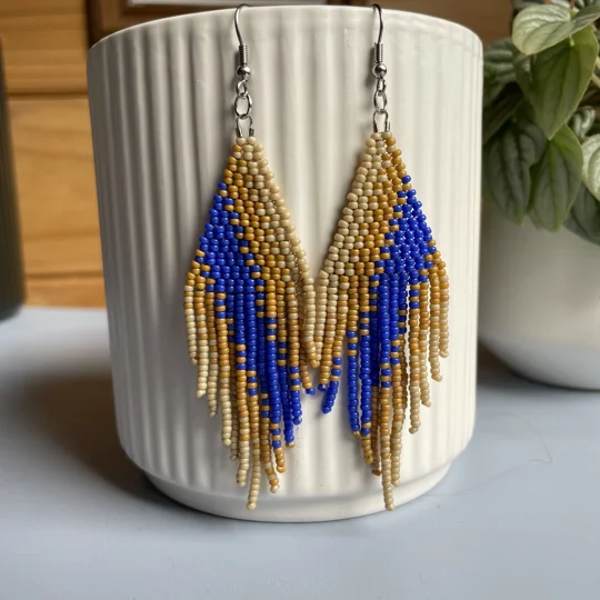 A pair of handmade beaded fringe earrings. Colors in a gradient Beige, Mustard, and Cobalt